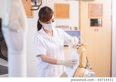 A woman in a white coat disinfecting a hospital room 69714431