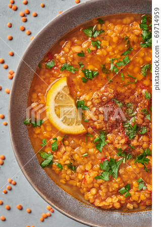 Red lentils tomato soup with parsley and lemon in gray plate on concrete table top. Vegetarian dish. 69714959