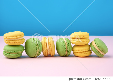 stack of yellow and green round almond flour cakes macarons with cream on a blue background 69715582