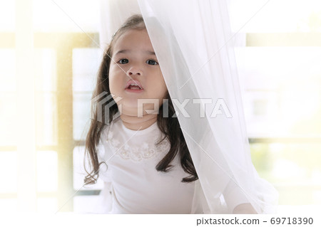 Little cute girl playing hide and seek with her parent.  69718390