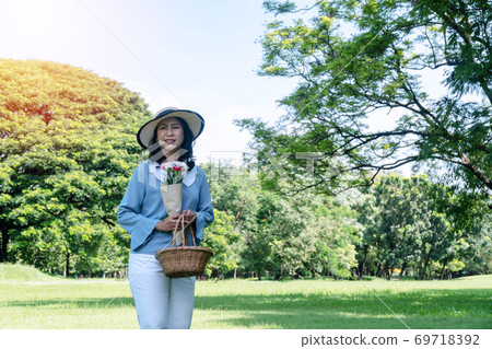 Elderly lifestyle concept. Cheerful smiling senior women 50s with hat while holding fruit basket  69718392