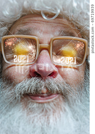 Close up Santa Claus in glasses with a reflection of 2021 Happy New Year Close up Santa Claus in glasses with a reflection of 2021 Happy New Year 69719939