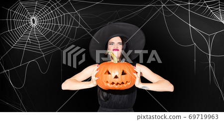 Young woman in hat as a witch on scary black background 69719963