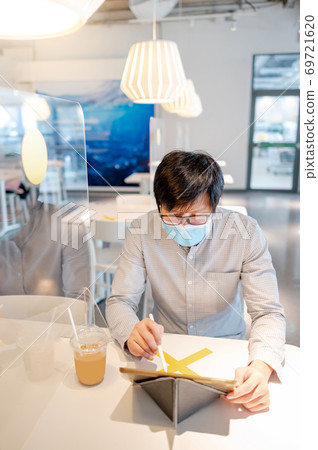 Asian man working in cafe with social distancing Asian man working in cafe with social distancing 69721620