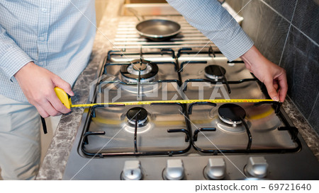 Male hand using tape measure on gas stove Male hand using tape measure on gas stove 69721640