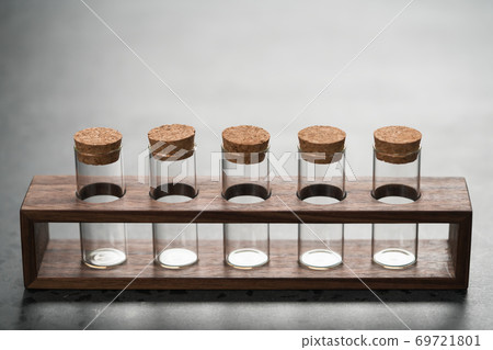 walnut holder with glass tubes for spices on concrete surface walnut holder with glass tubes for spices on concrete surface 69721801