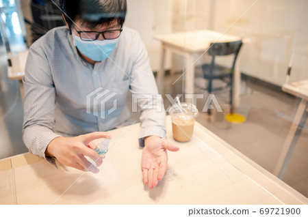 Cleaning hand with sanitizer spray in cafe Cleaning hand with sanitizer spray in cafe 69721900