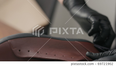 man hands in black gloves applying protective cream to brown leather sneakers man hands in black gloves applying protective cream to brown leather sneakers 69721902