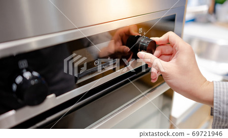 Male hand turning temperature knob of oven Male hand turning temperature knob of oven 69721946