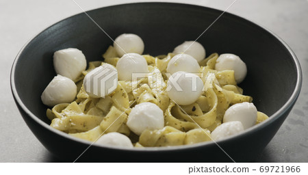 mozzarella with pesto fettuccine in black bowl on concrete countertop 69721966