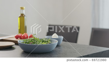 making salad in a blue bowl on concrete countertop on kitchen making salad in a blue bowl on concrete countertop on kitchen 69721980
