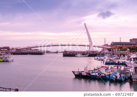 Many fishing boats dock at the pier near the sea-crossing bridge at dusk 69722487