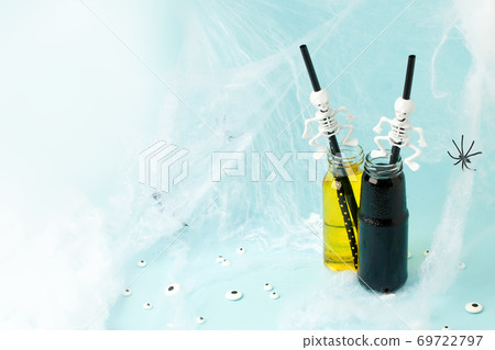 Colorful cocktails in glass bottles with skeleton straw on light blue background, Happy Halloween party banner, seasonal stylish holiday card, bright flyer Colorful cocktails in glass bottles with skeleton straw on light blue background, Happy Halloween party banner, seasonal stylish holiday card, bright flyer 69722797