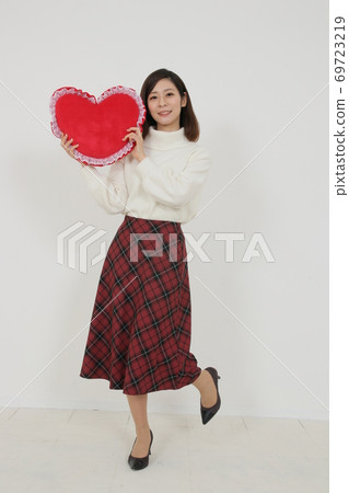 Young woman with red heart-shaped cushion 69723219