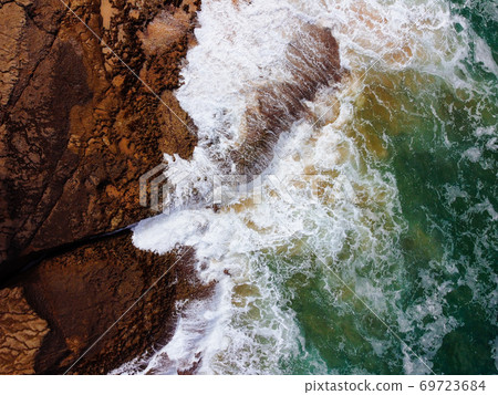 Aerial top view of sea waves hitting rocks on the cliffs 69723684