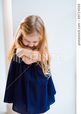 girl is upset and hugs herself by shoulders.   69724088