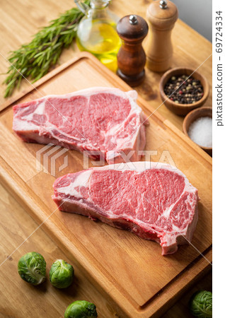 raw steak meat on cutting board in bright kitchen raw steak meat on cutting board in bright kitchen 69724334