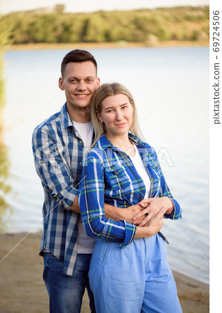 Young couple walks and enjoys the evening sun near the rive. Young couple walks and enjoys the evening sun near the rive. 69724506