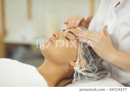 Woman getting procedure of relaxing facial massage treatment from cosmetologist Woman getting procedure of relaxing facial massage treatment from cosmetologist 69724877