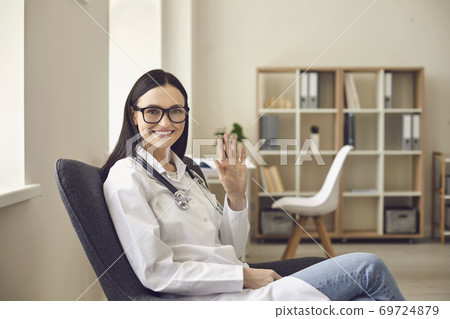 Doctor therapist looking at camera and greeting somebody during online meeting or videocall 69724879