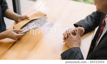 Businessman giving money while making deal to agreement a real estate contract and financial corporate.Bribery and corruption concept Businessman giving money while making deal to agreement a real estate contract and financial corporate.Bribery and corruption concept 69725054