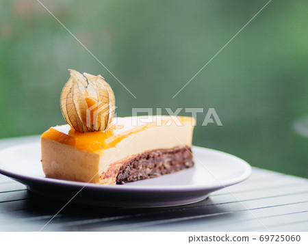 Closeup of delicious peach cake on the plate on green bokeh background 69725060