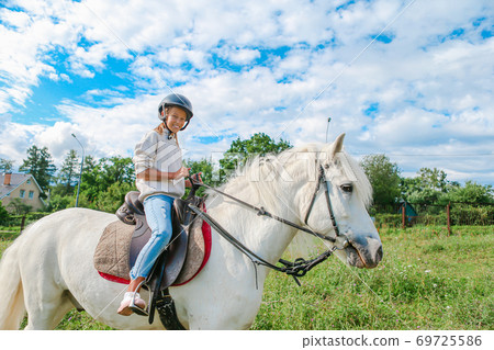 Girl riding a white horse on nature Girl riding a white horse on nature 69725586