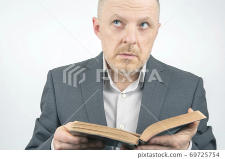 man in a business suit is reading the bible. man in a business suit is reading the bible. 69725754