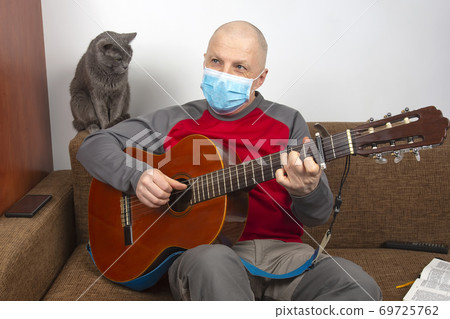 man in a medical mask at home in quarantine because of an epidemic of coronavirus man in a medical mask at home in quarantine because of an epidemic of coronavirus 69725762