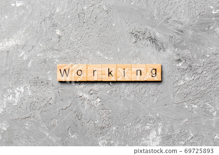 WORKING word written on wood block. WORKING text on cement table for your desing, concept WORKING word written on wood block. WORKING text on cement table for your desing, concept 69725893