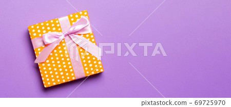 Top view Christmas present box with pink bow on purple background with copy space 69725970