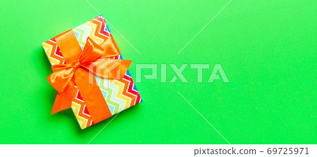 Top view Christmas present box with orange bow on green background with copy space 69725971