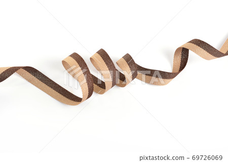 Brown beige Cotton ribbon, roll textilies on bobbin. strapping tape with curl on white backgroud. Brown beige Cotton ribbon, roll textilies on bobbin. strapping tape with curl on white backgroud. 69726069
