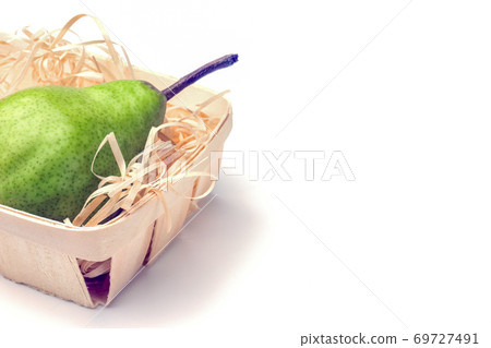 green pear in a basket close-up on a white background 69727491