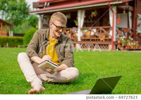 Happy young man studying remolety outdoors, watches business training courses Happy young man studying remolety outdoors, watches business training courses 69727623