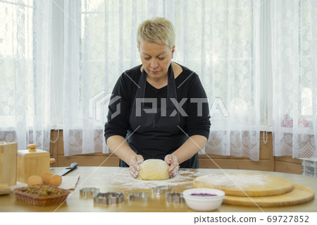Caucasian beautyful woman housewife kneading dough on wooden antique table. 69727852