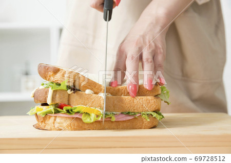 Woman cutting a sandwich Woman cutting a sandwich 69728512