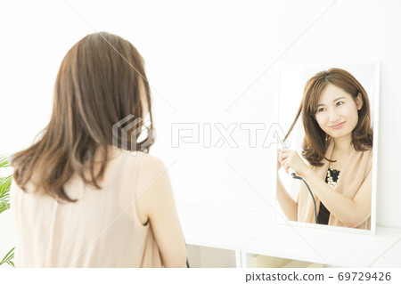 A woman using a hair iron A woman using a hair iron 69729426