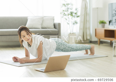 A woman training at home while looking at a computer A woman training at home while looking at a computer 69729506