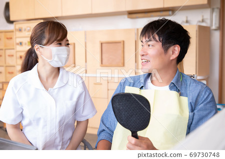 Dental hygienist and male patient 69730748