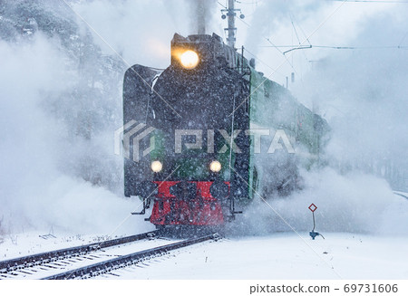 Retro steam train approaches to the railway station. Retro steam train approaches to the railway station. 69731606