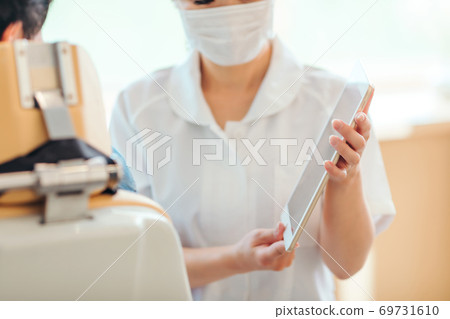 Dental hygienist and male patient 69731610
