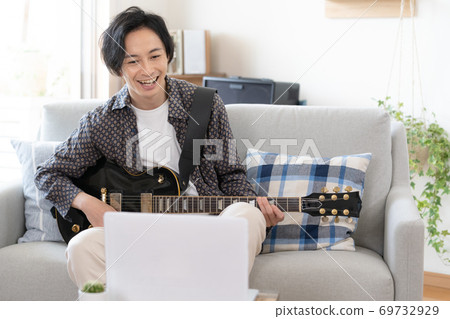 A man playing a band online [at home] 69732929