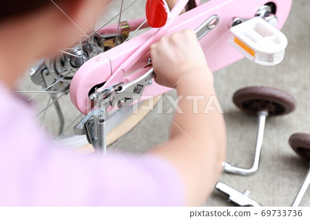 Woman removing training wheels and stand on bicycle 69733736