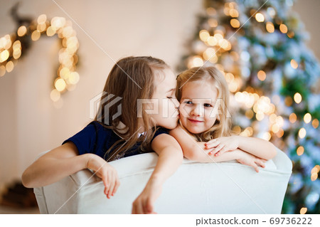 girls in chair on background of Christmas tree. 69736222