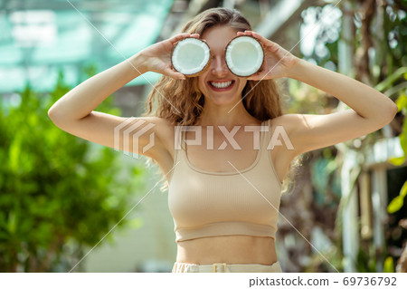 Pretty young long-haired woman closing her eyes with coconut Pretty young long-haired woman closing her eyes with coconut 69736792