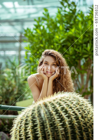 Pretty young woman standing near the cactus and looking thoughtful 69736812
