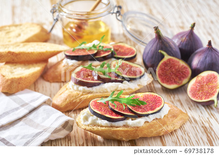 vegetarian breakfast with fig, cream cheese and honey on a wooden table. vegetarian breakfast with fig, cream cheese and honey on a wooden table. 69738178