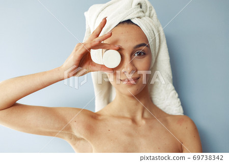 Beautiful girl standing in a studio with cream Beautiful girl standing in a studio with cream 69738342