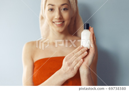 Beautiful girl standing in a studio with cream Beautiful girl standing in a studio with cream 69738380